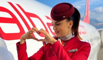 Niña haciendo un signo de corazón en un avión albanés.