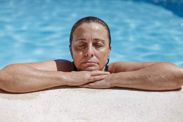 Woman resting by the pool, emphasizing relaxation and wellness.
