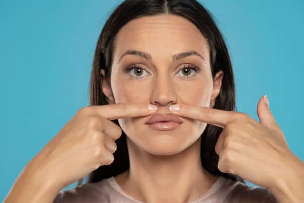 Woman demonstrating lip lift and fillers for cosmetic lip enhancement.