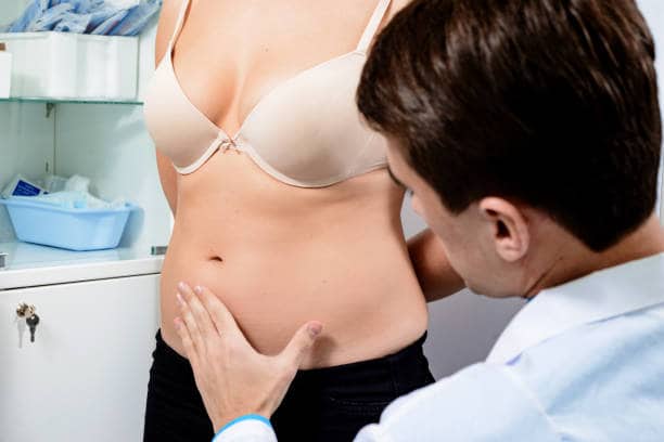 Médico examinando el abdomen de una mujer para evaluación médica en Albania.